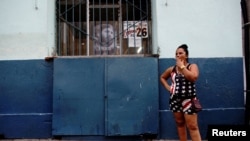 Una mujer fuma junto a una imagen de Fidel Castro. REUTERS/Alexandre Meneghini
