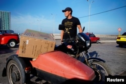 Un hombre lleva en su motocicleta la consola de aire acondicionado que compró este lunes en una de las tiendas en dólares abiertas por el gobierno en La Habana. REUTERS/Alexandre Meneghini