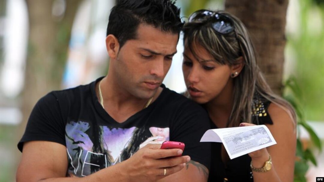 Dos jóvenes usan un teléfono móvil en La Habana.