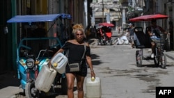 Una mujer transporta recipientes de agua durante un apagón en La Habana, el 7 de julio de 2026.