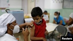Luis Duarte, de 5 años, recibe una dosis de la vacuna Sinopharm contra la enfermedad del coronavirus (COVID-19) para asegurar la protección contra la variante del coronavirus ómicron, en Caracas, Venezuela, el 9 de diciembre de 2021.