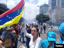 La opositora María Corina Machado sostiene una bandera venezolana al revés en protesta contra el gobierno de Maduro.