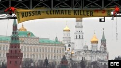 ARCHIVO. Activistas de Greenpeace colocan un afiche gigante con el mensaje 'Rusia - Asesino del Clima' en un puente sobre el río Moskva, frente al Kremlin de Moscú.