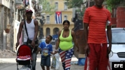 Una mujer vestida con la bandera de Estados Unidos camina junto a su familia en una calle de La Habana (Cuba).