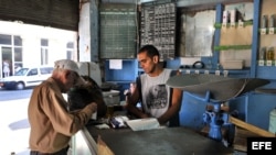 Un bodeguero vende productos racionados a un cliente en La Habana. 
