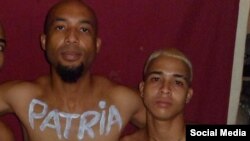 El activista Osmani Pardo Guerra, junto con su primo, con el título de la canción "Patria y Vida" escrito en el cuerpo.