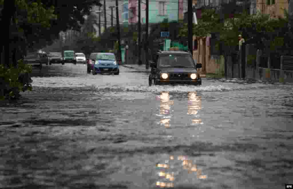 Vehículos transitan por una calle inundada hoy, viernes 29 de noviembre de 2013, en La Habana