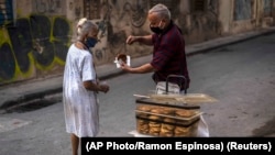 Una mujer compra un dulce a un vendedor ambulante en La Habana en medio del repunte de contagios de coronavirus. (AP Photo/Ramon Espinosa)