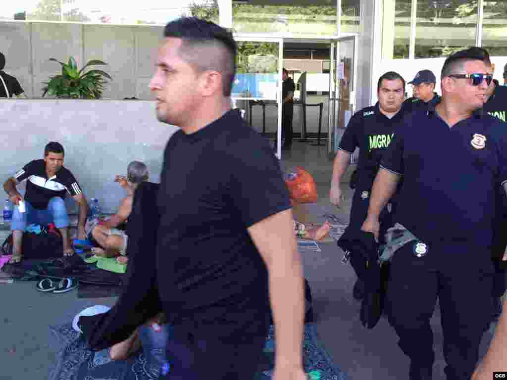 Agentes de la Policía de Migración caminan entre un grupo de cubanos.