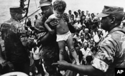 Un marine de EEUU ayuda a desembarcar a un niño cubano tras su llegada a las costas de Florida en el éxodo del Mariel. AP Photo/Fernando Yovera)