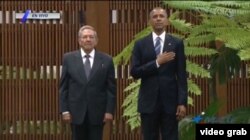 El presidente Barack Obama y Raúl Castro escuchan los himnos nacionales de los Estados Unidos y Cuba.