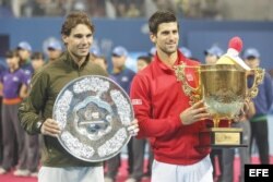 Novak Djokovic de Serbia (d) muestra el trofeo de campeón después de derrotar a Rafael Nadal de España (i) en la final individual masculina del Abierto de China, en el Centro Nacional de Tenis en Beijing.