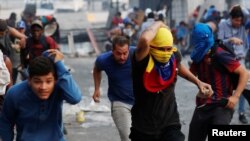 Manifestantes huyen durante un enfrentamiento con la fuerzas de seguridad durante una protesta en Caracas el 30 de abril de 2019. 