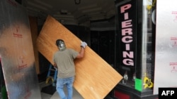 Los contratistas colocan madera contrachapada sobre las ventanas de un salón en Ybor City, Tampa, antes de la llegada del huracán Milton.