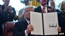 Donald Trump muestra el documento firmado con su veto.