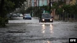 Vehículos transitan por una calle inundada hoy, viernes 29 de noviembre de 2013, en La Habana