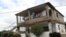 Un hombre camina junto a una casa que se encuentra a la venta.