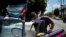 Un empleado de una compañía privada desinfecta un auto clásico en una calle de la Havana Vieja. (YAMIL LAGE/AFP)