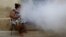Una mujer fuma mientras soldados fumigan su vivienda para eliminar el agente transmisor del dengue y zika en La Habana. (Archivo-REUTERS/Ueslei Marcelino)