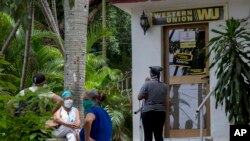 Varias personas permanecen afuera de una oficina de la Western Union, en el Vedado, La Habana. (AP/Ismael Francisco)