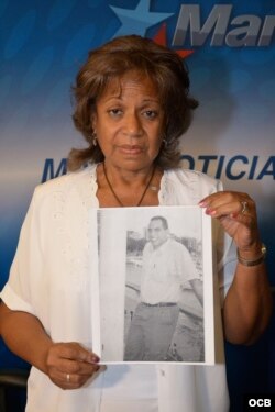 Lilia Castañer, dama de blanco, muestra la foto de su hijo desaparecido en España.