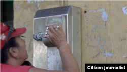 Reporta Cuba. Una mujer intenta comunicarse desde un teléfono público en Centro Habana.