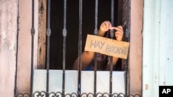 FOTO ARCHIVO. Un cubana anuncia con un cartel la venta de bocaditos desde su ventana. (AP Photo/Desmond Boylan)