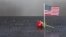 Una bandera estadounidense y una rosa roja, puestas en la placa con los nombres de los fallecidos.