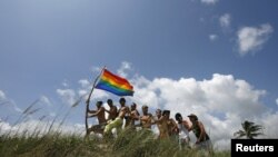 Un grupo de hombres posa con la bandera del movimiento gay en una playa de Cuba. 