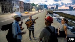 Cantantes cubanos cantan un bolero a una mujer en el malecón de La Habana, el 4 de diciembre de 2023. YAMIL LAGE / AFP