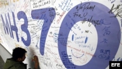Un hombre escribe mensajes en honor a las víctimas del vuelo MH370 de Malaysia Airlines en el aeropuerto internacional de Kuala Lumpur (marzo, 2014).