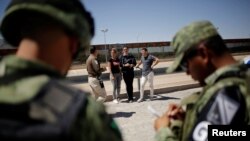 Un agente del Instituto Nacional de Inmigración (INM) de México habla con cubanos detenidos por la Guardia Nacional mientras intentaban cruzar ilegalmente la frontera en Ciudad Juárez el 21 de junio de 2019 (Archivo).