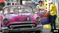 Un grupo de turistas pasea en un auto clásico con una pegatina de Ernesto Guevara. EFE
