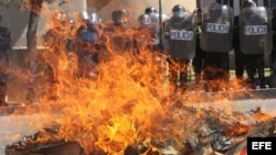 Estudiantes queman muñecos y un ataúd frente a la policía durante una protesta en apoyo a los médicos de Bolivia. 