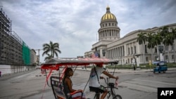 Un bicitaxi decorado con una bandera estadounidense pasa frente al Capitolio de La Habana el 11 de julio de 2026.