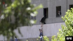 Policías iraníes ayudan a escapar a civiles después de que varios hombres armados irrumpieran en el Parlamento iraní.