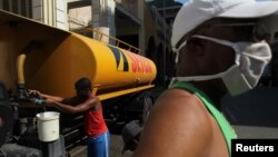 Cubanos almacenan agua en La Habana en medio de la crisis por el coronavirus. Las autoridades están amenazando y multando a miembros de la sociedad civil que reporten sobre la situación de la pandemia en la isla.
