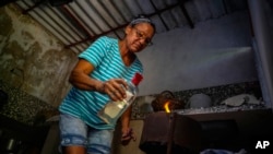 Rosa López enciende una estufa de carbón en Mariel, Cuba, el 18 de mayo de 2023. (Foto AP/Ramon Espinosa)