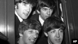 El grupo pop británico The Beatles, desde arriba a la izquierda, John Lennon, George Harrison, Paul McCartney y Ringo Starr, posan en la ventanilla de un vagón en la estación de Paddington en Londres, el 2 de marzo de 1964. (AP Photo/Bob Dear, File)
