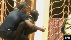 Un rehén herido es trasladado por personal militar de Mali a su salida del hotel de lujo Radisson Blu. EFE