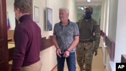 Robert Shonov camina esposado y escoltado por agentes hacia una sala de la Corte del Distrito Lefortovo