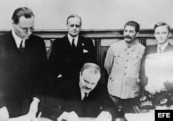 Moscú, 23-8-1939.- Viacheslav Molotov, ministro de Asuntos Exteriores de la URSS, firma en Moscú el pacto de No Agresión entre Alemania y la Unión Soviética. Tras él, su homólogo alemán, Joachim von Ribbentrop, y al lado de éste, Josef Stalin (2º d.)