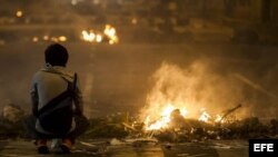 20/02/2014.- Un hombre permanece junto al fuego de las barricadas durante una protesta contra el Gobierno del presidente venezolano