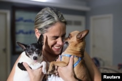 Karolina Vásquez Ramírez con sus perros Bingo y Dasha en su casa antes de partir hacia el aeropuerto, en La Habana, Cuba, el 25 de octubre de 2023. REUTERS/Carlos Carrillo