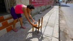 Una mujer pone a cargar un panel solar en medio del apagón, en La Habana. 