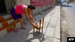 Una mujer pone a cargar un panel solar en medio del apagón, en La Habana. 