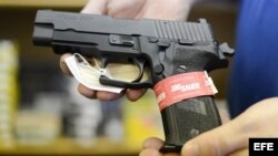 Un propietario de una armería muestra una pistola semiautomática Sig Sauer en su negocio.