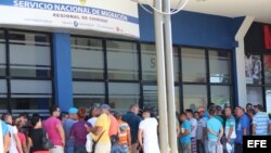 Migrantes cubanos esperan hoy, domingo 21 de febrero de 2016, a las puertas de la oficina de Migración de David, para recibir en sus pasaportes un permiso migratorio para poder salir legalmente de Panamá hacia México, desde donde cruzarán a Estados Unidos