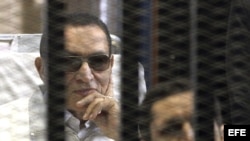 Foto de archivo del expresidente egipcio, Hosni Mubarak (izq), mientras comparece desde una celda en la sala del tribunal a una sesión de su juicio en la Academia de la Policía en El Cairo