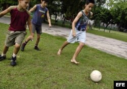 Varios niños cubanos juegan con un balón de fútbol.